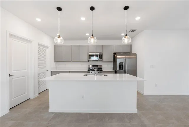 a view of a kitchen with kitchen island stainless steel appliances sink and wooden floor