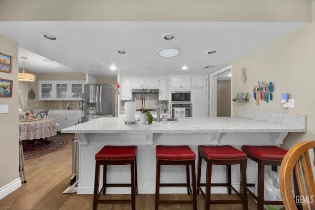 a kitchen with stainless steel appliances granite countertop a table chairs sink and cabinets