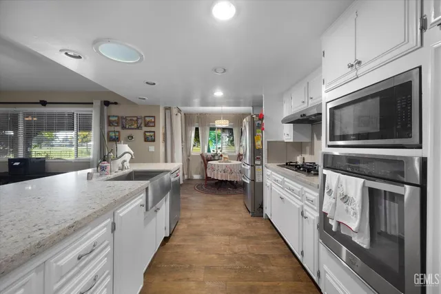 a large kitchen with stainless steel appliances granite countertop a lot of counter space and wooden floor