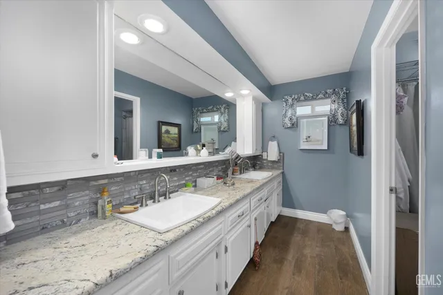 a spacious bathroom with a granite countertop double vanity sink a mirror and a shower