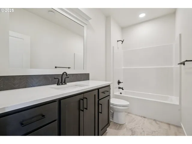 a bathroom with a granite countertop sink a toilet and a large mirror