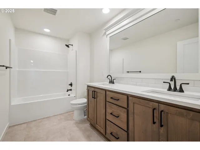 a bathroom with a double vanity sink a toilet and a bathtub
