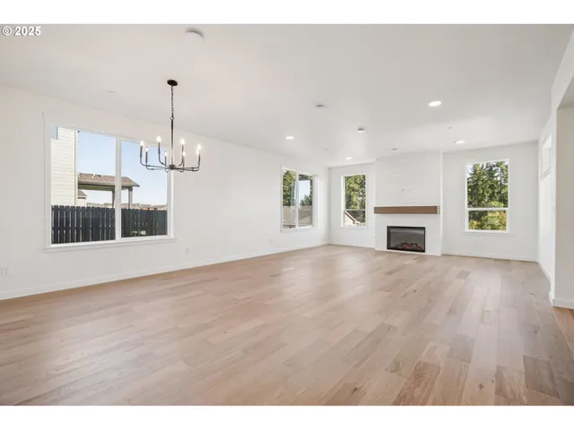 a view of empty room with wooden floor and kitchen view