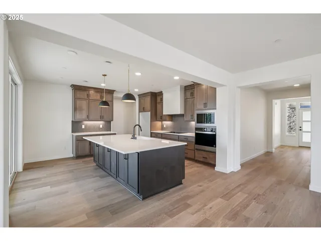 a large kitchen with a lot of counter top space wooden floor and stainless steel appliances