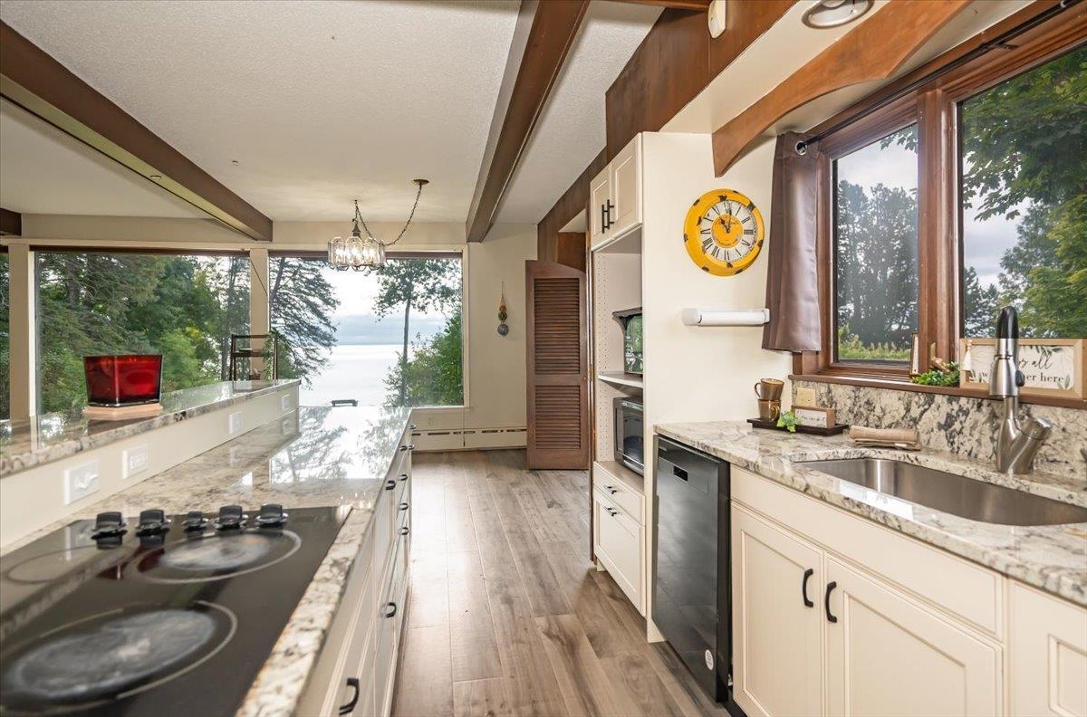5130 London Road Duluth, MN 55804 - Photo 14 of 45 Kitchen with beamed ceiling, black appliances, light stone countertops, healthy amount of natural light, and light wood-style flooring