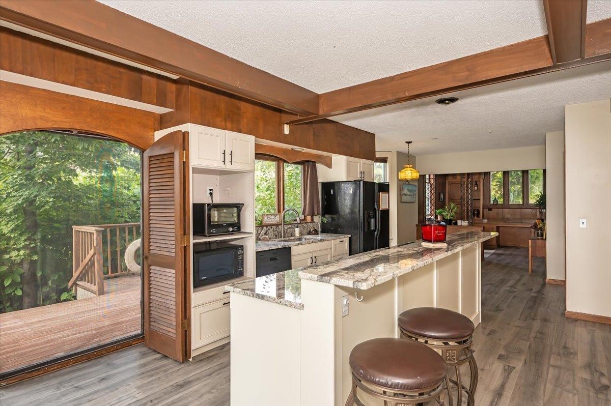 5130 London Road Duluth, MN 55804 - Photo 16 of 45 Kitchen featuring dark wood finished floors, white cabinets, beamed ceiling, light stone counters, and black appliances