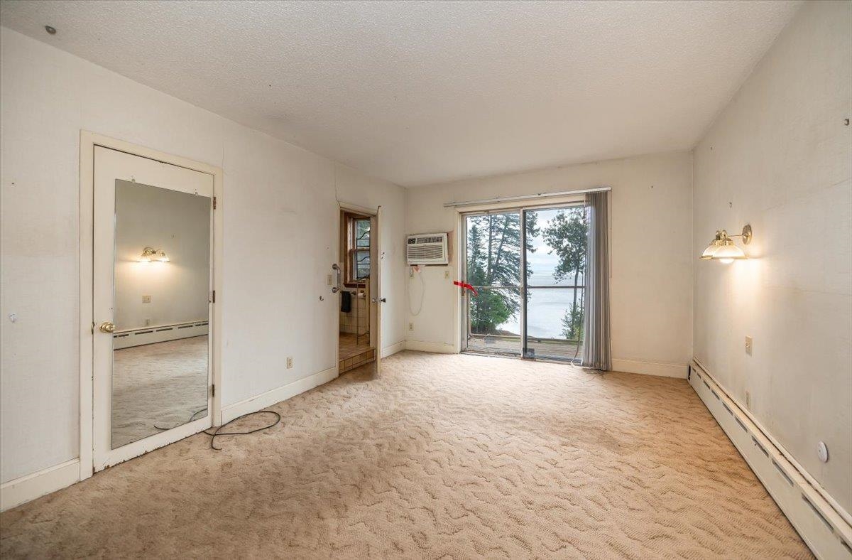 5130 London Road Duluth, MN 55804 - Photo 24 of 45 Carpeted spare room with a baseboard radiator, a textured ceiling, and a wall unit AC