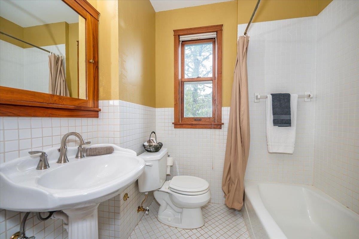 5130 London Road Duluth, MN 55804 - Photo 26 of 45 Full bath featuring tile walls, tile patterned flooring, shower / bath combo with shower curtain, and wainscoting
