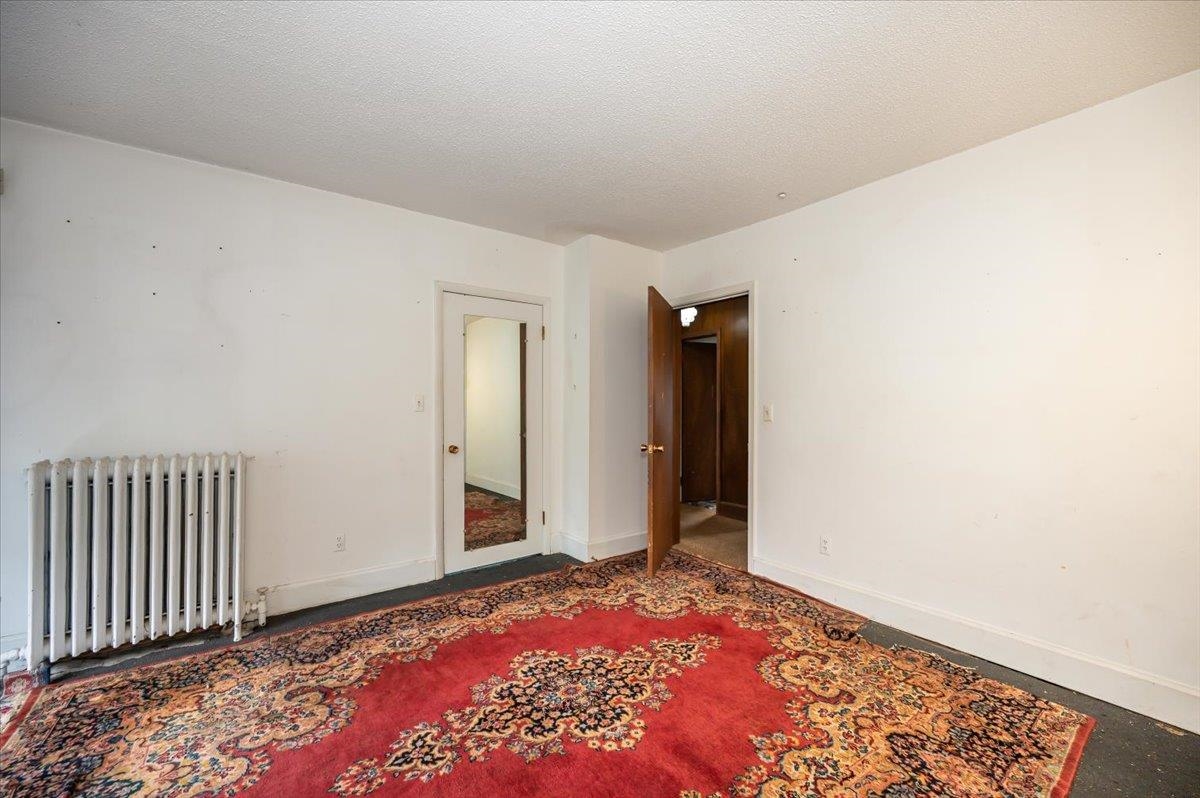 5130 London Road Duluth, MN 55804 - Photo 28 of 45 Empty room featuring radiator heating unit and a textured ceiling