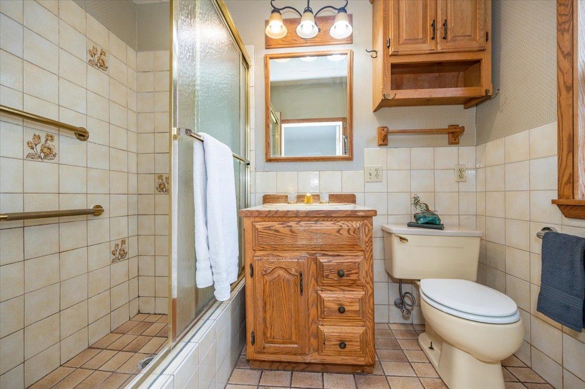 5130 London Road Duluth, MN 55804 - Photo 29 of 45 Bathroom featuring vanity, a stall shower, light tile patterned floors, tile walls, and wallpapered walls