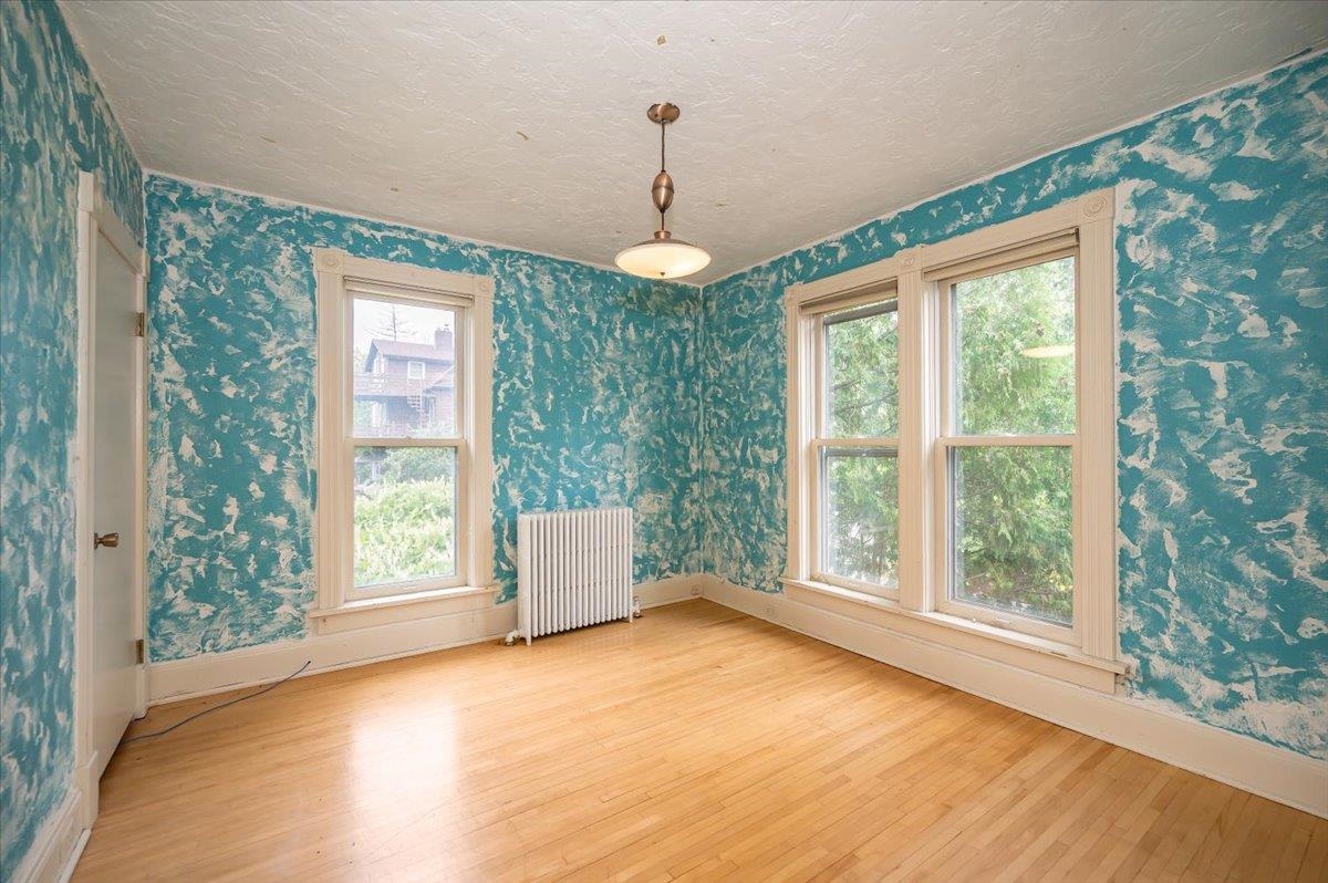 5130 London Road Duluth, MN 55804 - Photo 30 of 45 Unfurnished room with wallpapered walls, wood finished floors, radiator, and a textured ceiling