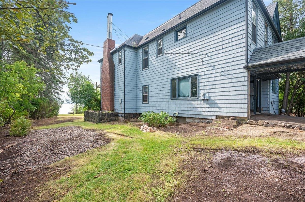 5130 London Road Duluth, MN 55804 - Photo 4 of 45 A side view of the property features a chimney, a roof with shingles, and two updated lined stainless steel flue pipes.