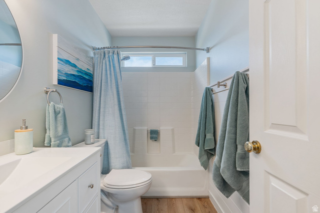 14883 Tooele Lane Draper, UT 84020 - Photo 33 of 49 Bathroom featuring a white vanity with integrated sink, wood-finish flooring, and a shower-tub combination with a transom window