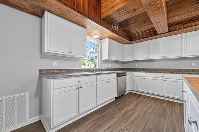 a kitchen with granite countertop wooden floors white cabinets and white appliances