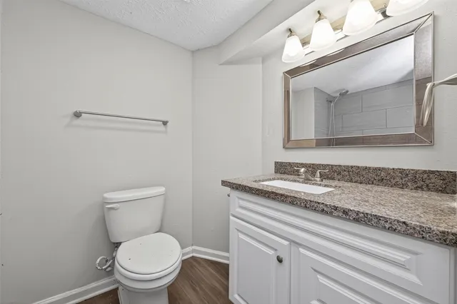 a bathroom with a granite countertop toilet sink and mirror