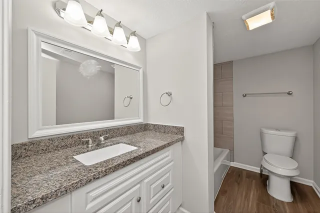a bathroom with a granite countertop sink a toilet and a mirror