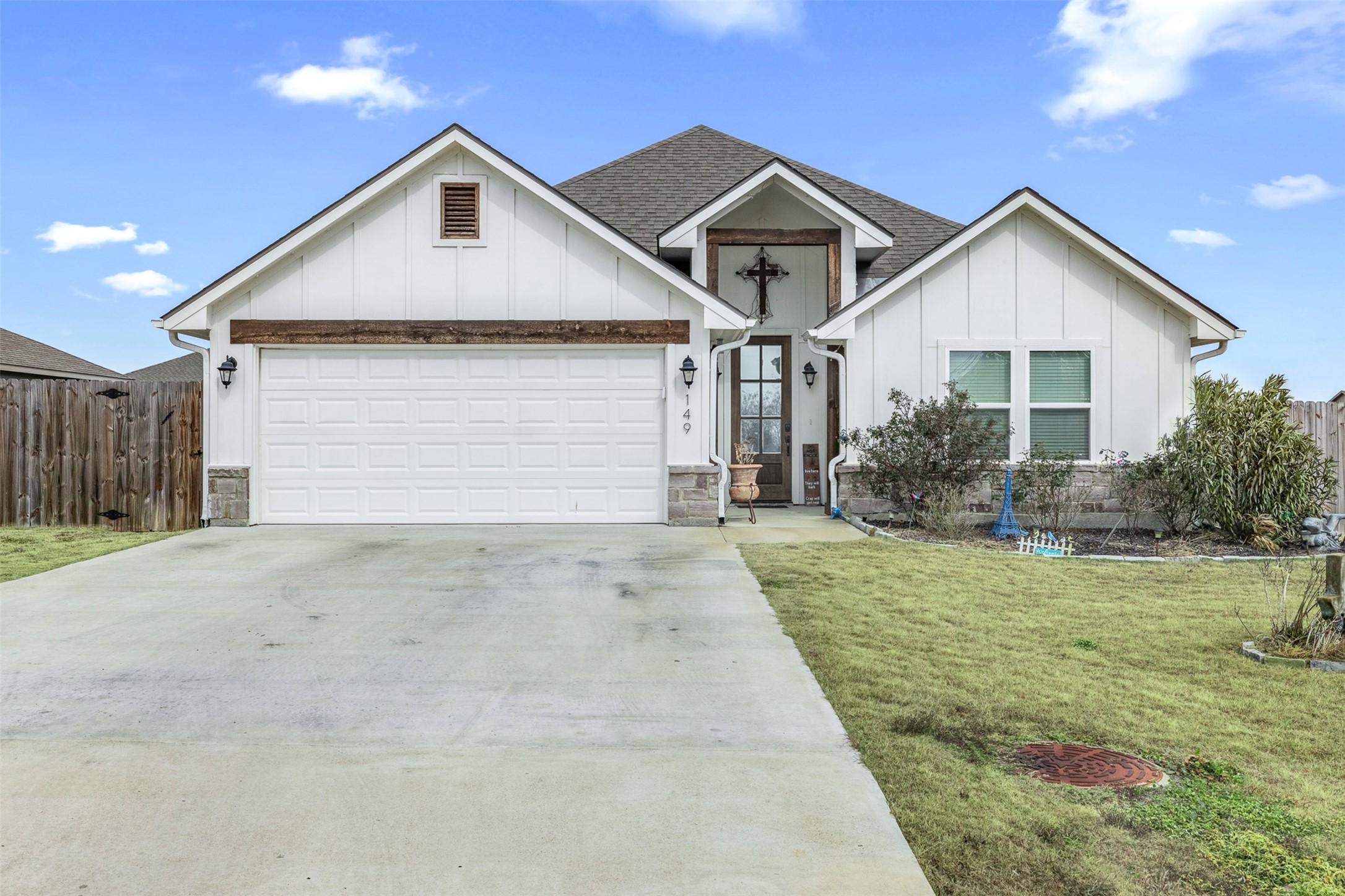 View of front of home with board and batten siding, roof with shingles, stone siding, driveway, and an attached garage