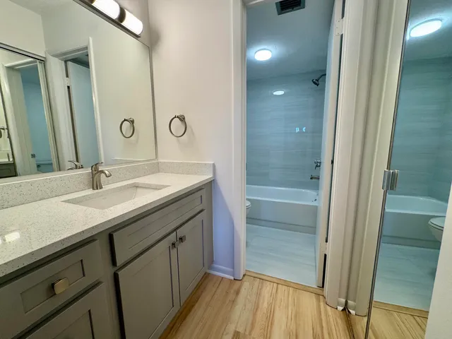 a bathroom with a granite countertop sink a mirror and a bathtub