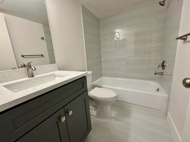 a bathroom with a granite countertop sink a toilet a bathtub and shower