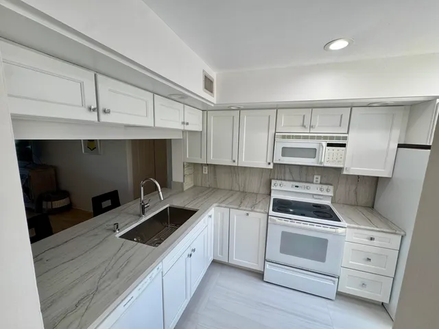a kitchen with white cabinets and white appliances