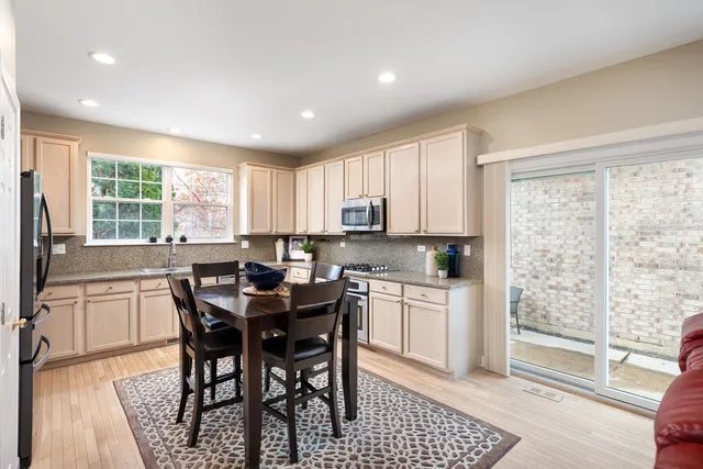 a kitchen with stainless steel appliances granite countertop a stove a sink a microwave a dining table and chairs