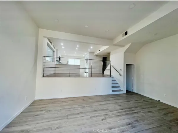 a view of kitchen and empty room with wooden floor