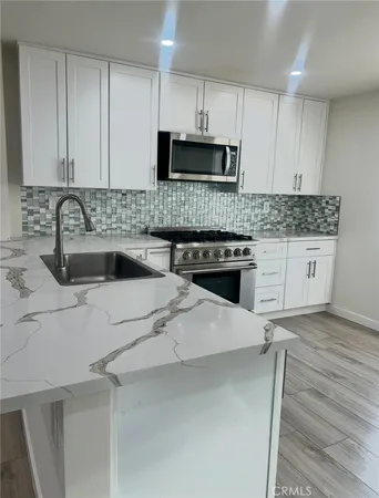 a kitchen with stainless steel appliances a sink a stove a microwave and cabinets