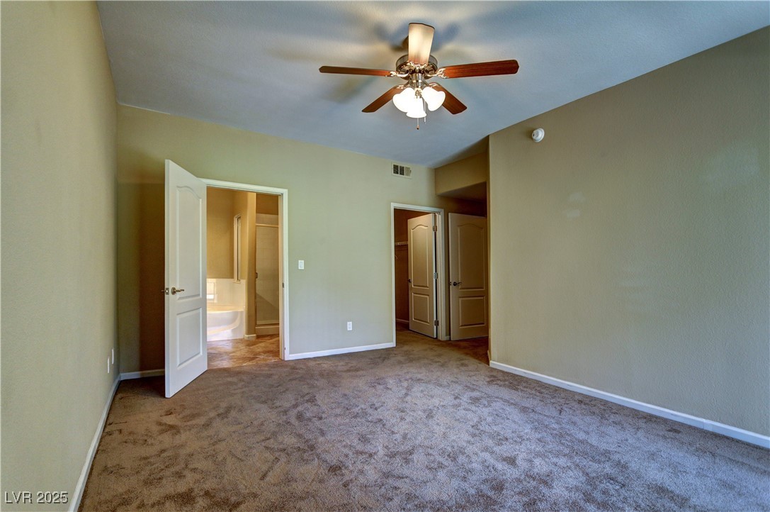 10225 King Henry Avenue, Unit 104 Las Vegas, NV 89144 - Photo 12 of 24 Unfurnished bedroom with carpet, a ceiling fan, and a spacious closet