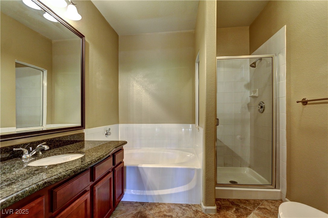 10225 King Henry Avenue, Unit 104 Las Vegas, NV 89144 - Photo 13 of 24 Bathroom featuring a bath, vanity, a stall shower, light tile patterned floors, and a textured wall