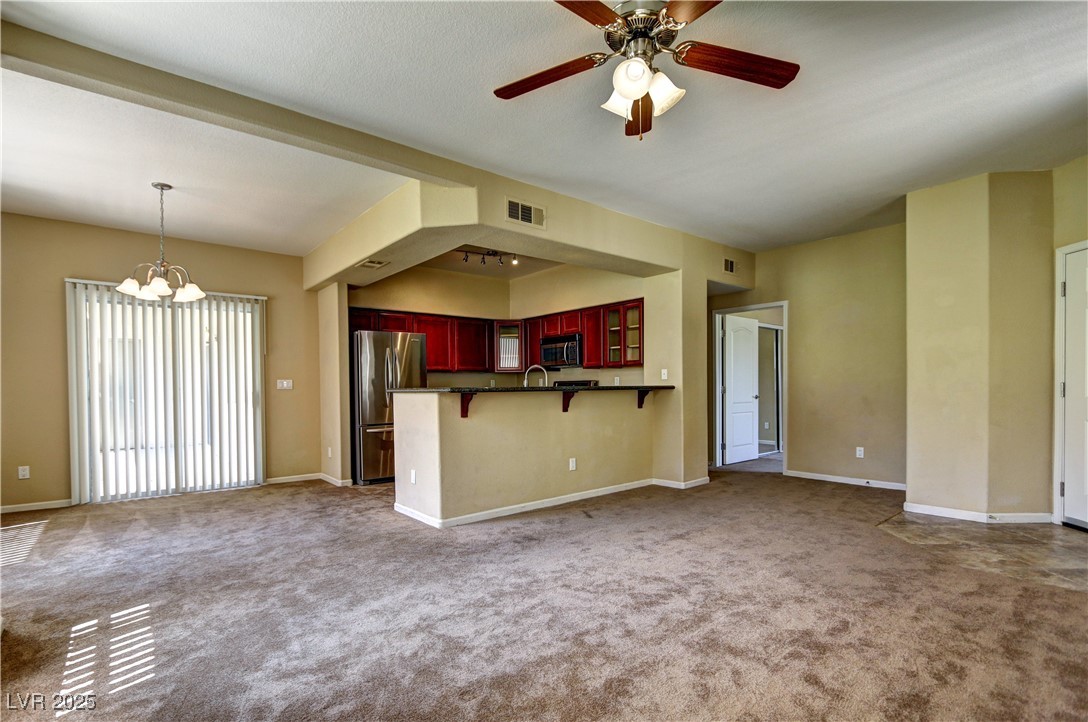 10225 King Henry Avenue, Unit 104 Las Vegas, NV 89144 - Photo 5 of 24 Unfurnished living room with carpet, a chandelier, and a ceiling fan