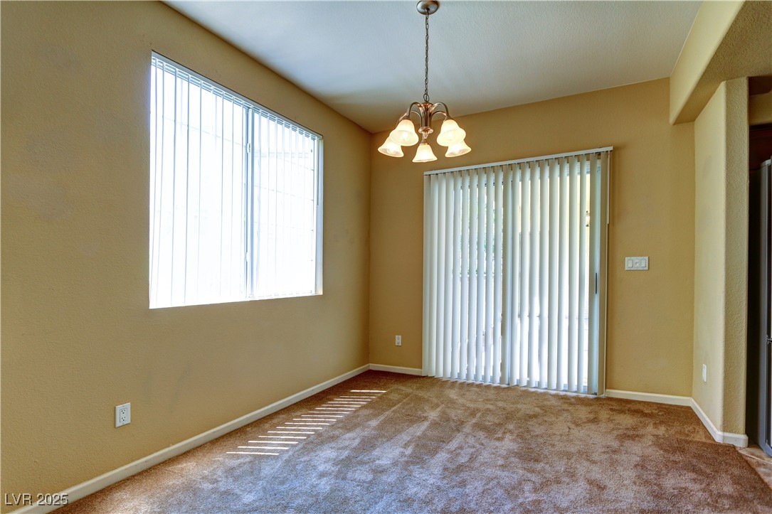 10225 King Henry Avenue, Unit 104 Las Vegas, NV 89144 - Photo 7 of 24 Carpeted spare room with a chandelier and baseboards