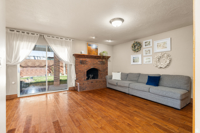 892 Cambridge Drive St. George, UT 84770 - Photo 28 of 65 Living space featuring wood-finish flooring, a brick fireplace with a wood mantel, and sliding glass doors