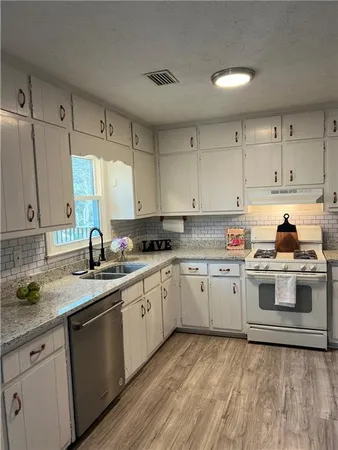 a kitchen with granite countertop white cabinets and white appliances