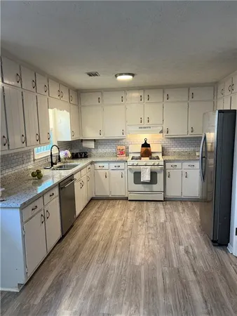a kitchen with wooden floors and white stainless steel appliances