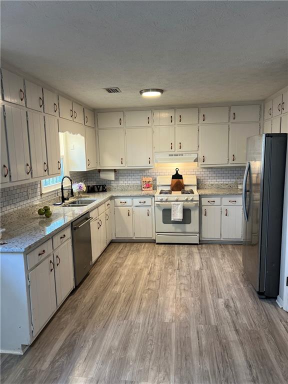 3221 Bromley Rowe Duluth, GA 30096 - Photo 17 of 44 a kitchen with wooden floors and white stainless steel appliances