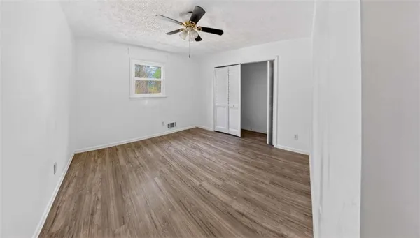 a view of empty room with wooden floor and fan