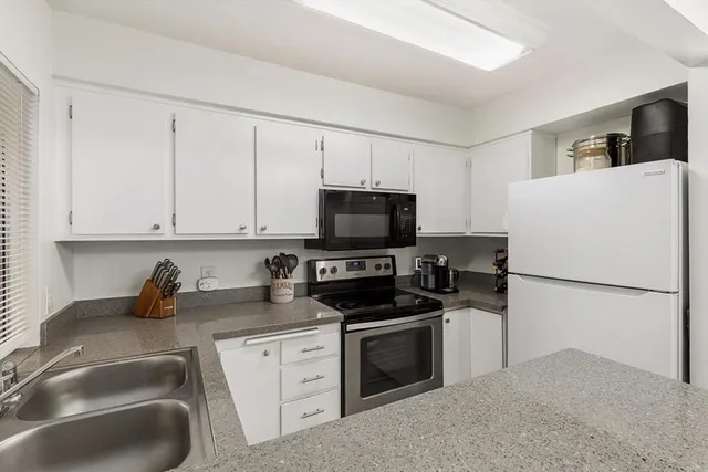 a kitchen with granite countertop a sink a stove a microwave and refrigerator