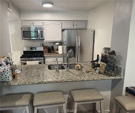 a kitchen with stainless steel appliances granite countertop a sink refrigerator and cabinets
