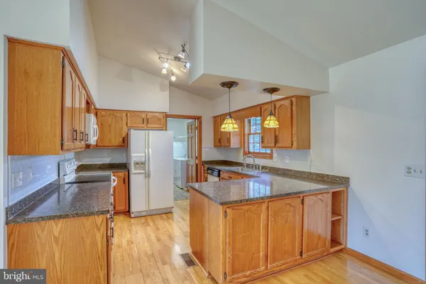 a kitchen with stainless steel appliances granite countertop a sink refrigerator and cabinets