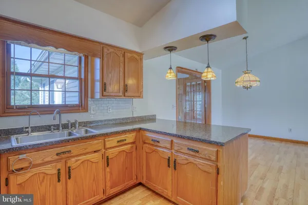 a kitchen with stainless steel appliances granite countertop a sink cabinets and wooden floor