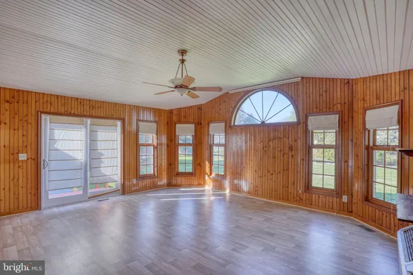 an empty room with wooden floor chandelier and windows