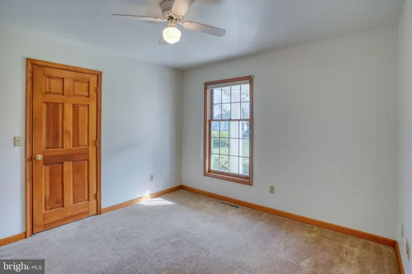 an empty room with windows closet and chandelier fan