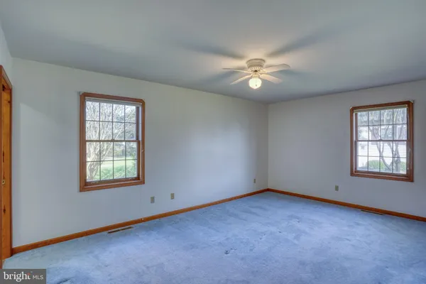 an empty room with windows and ceiling fan