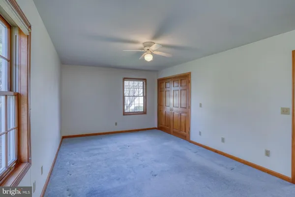 an empty room with windows and fan