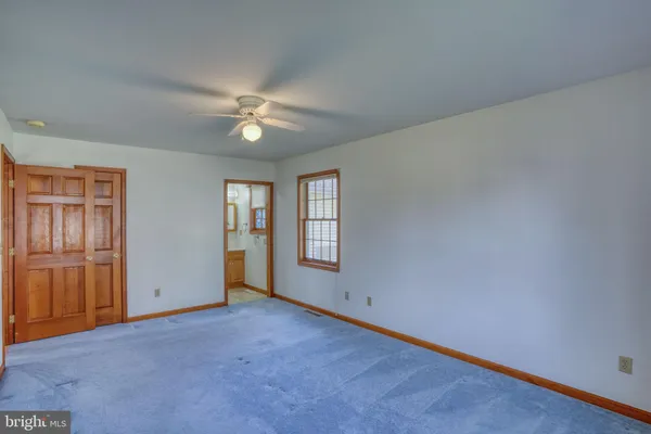 an empty room with chandelier fan and windows