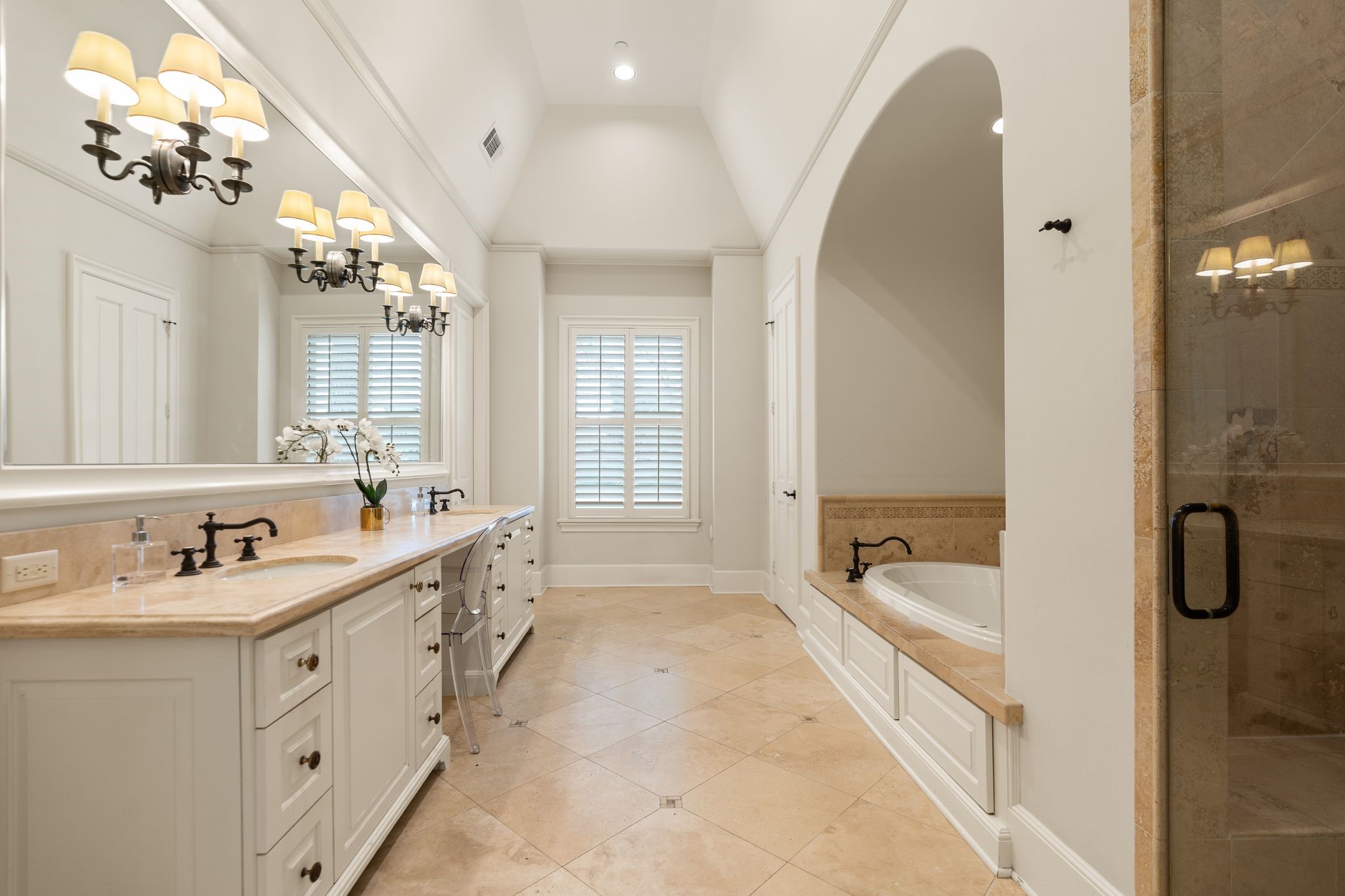 11402 Taylorcrest Road Houston, TX 77024 - Photo 21 of 44 Spacious primary bath features an expansive vanity w/ limestone countertop, dual sinks, abundant storage & dedicated vanity knee space. Decorative sconces & plantation shutters add warmth & architectural character. Dual large walk-in closets w/ built-in dressers provide exceptional organization. Oversized air jet tub & separate shower w/ frameless glass door & bench seat. Private water closet.