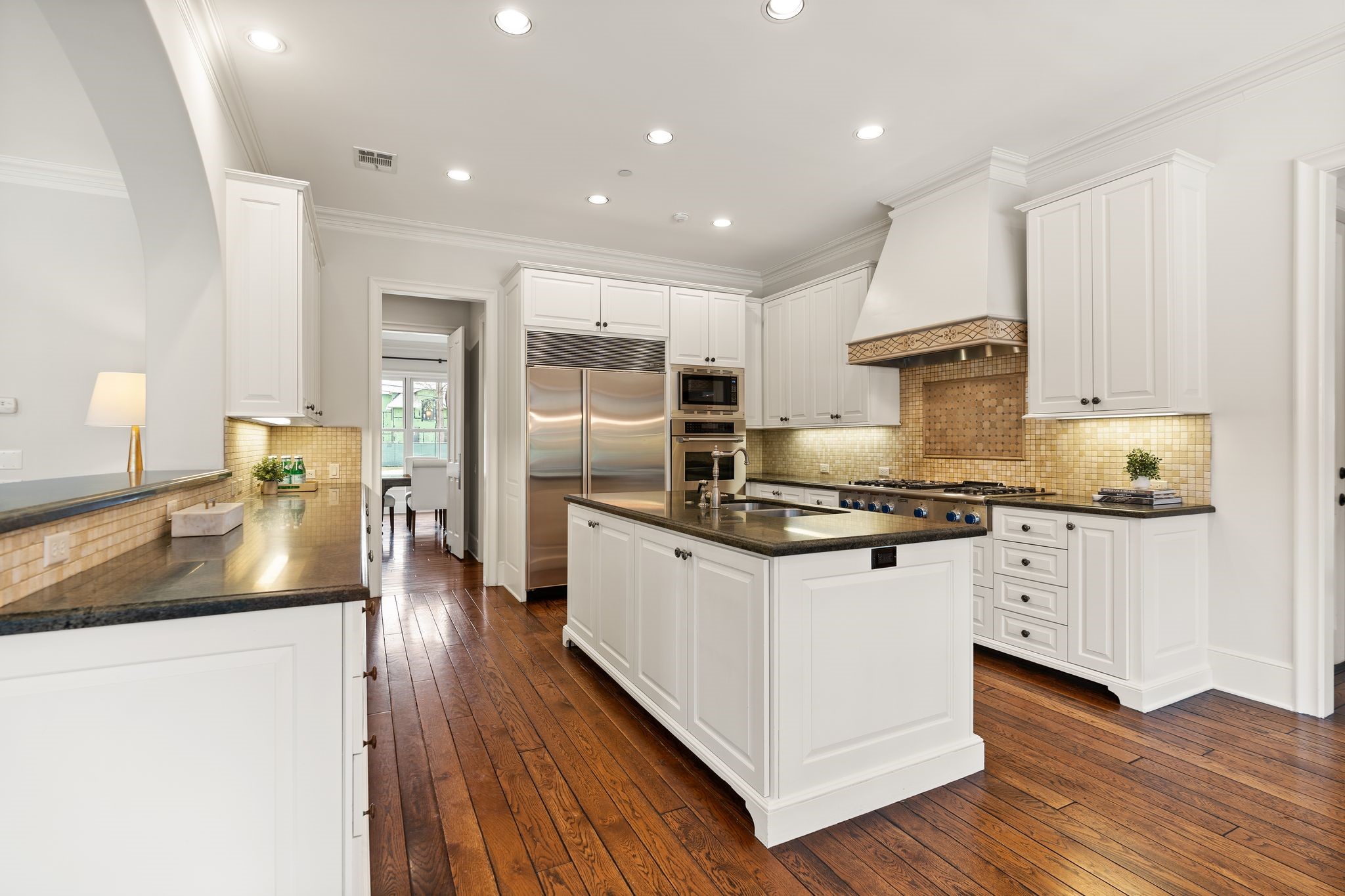 11402 Taylorcrest Road Houston, TX 77024 - Photo 10 of 44 Beautiful kitchen features honed granite countertops & tile backsplash, complemented by abundant cabinetry, offering exceptional storage & workspace. Under-cabinet lighting & pull-out trash drawer enhance everyday efficiency while maintaining a clean, functional aesthetic.