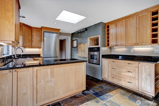 a kitchen with stainless steel appliances granite countertop a stove a sink and a microwave