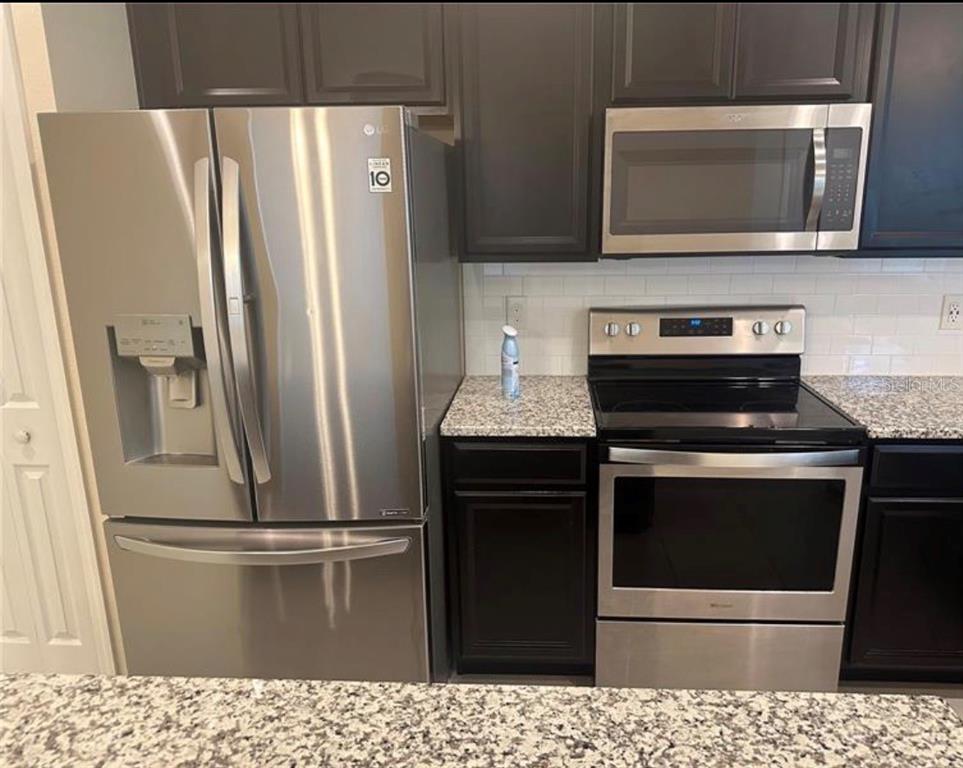 4851 Cliveden Loop Sanford, FL 32773 - Photo 4 of 24 a kitchen with a stove microwave and refrigerator