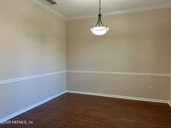 a view of an empty room with wooden floor and cabinets